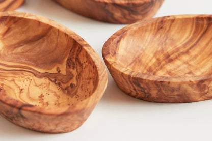 Close-up of two olivewood condiment bowls showing the dark irregular grain unique to each piece