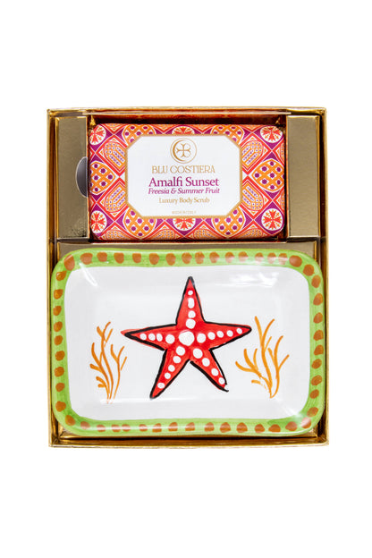 Amalfi Sunset gift box from above: the Freesia and Summer Fruit luxury body scrub in patterned wrapping above a hand-painted Vietri ceramic soap dish with a red starfish flanked by orange coral