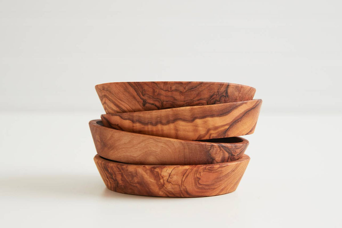 Set of four Italian olivewood condiment bowls stacked, showing the varied honey-to-amber grain of each piece