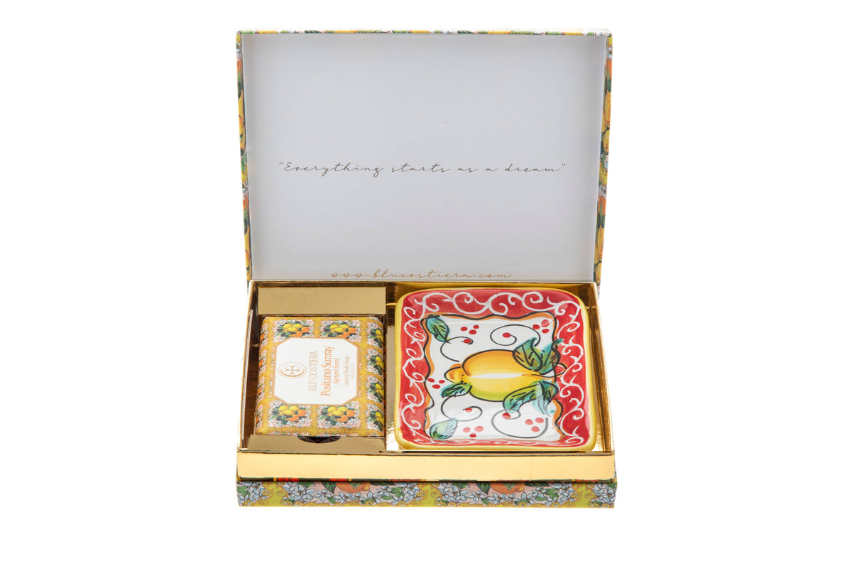 Open Positano Sunray gift box with the lid printed 'Everything starts as a dream', holding a boxed body soap and a square hand-painted Vietri ceramic soap dish with a lemon design on a red border