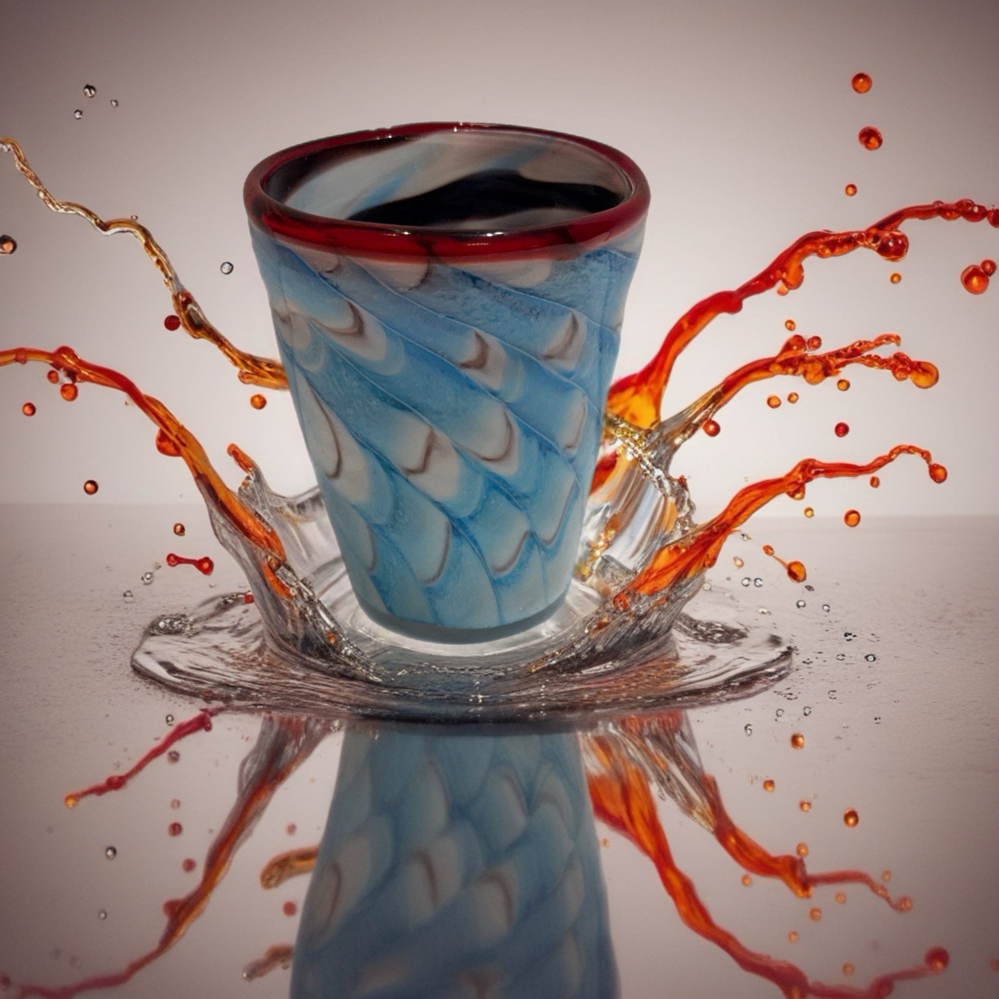 Hand-blown Italian glass tumbler with blue and white swirl pattern and red rim