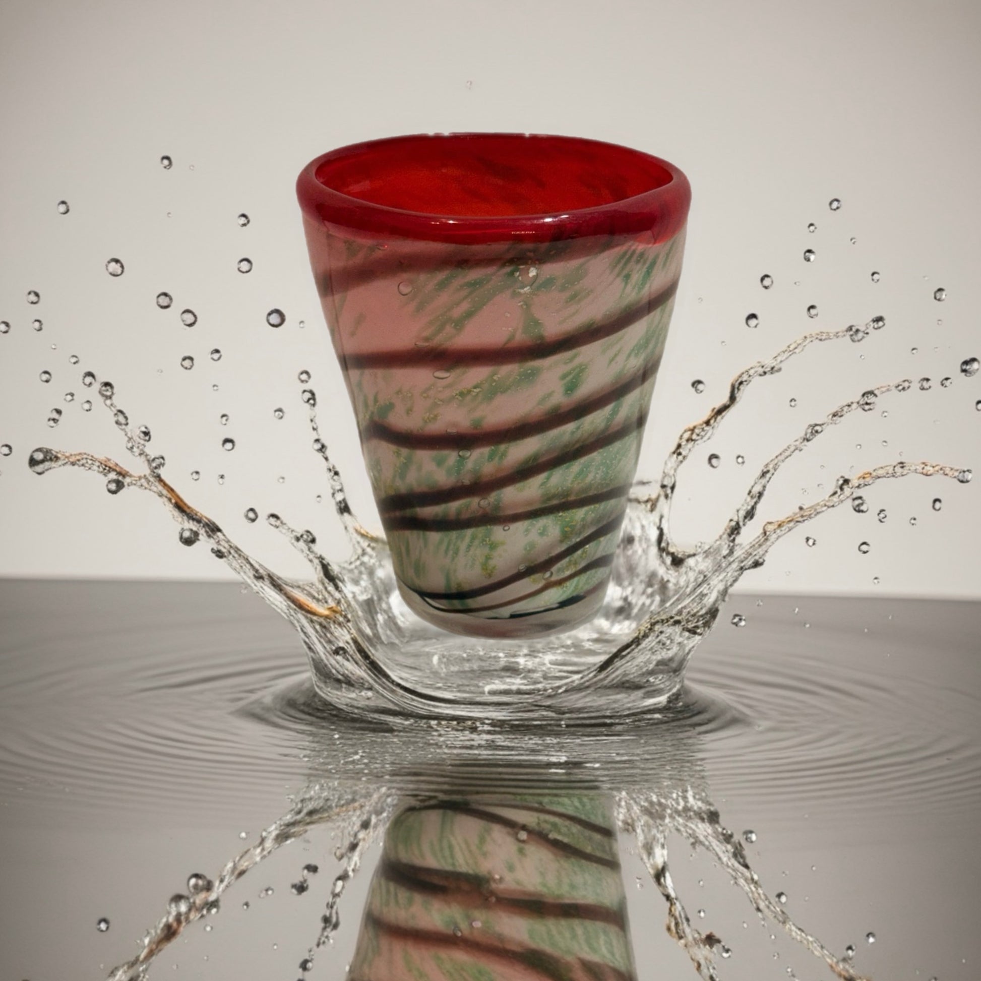 Hand-blown Italian glass tumbler with green and ivory swirl pattern and red rim