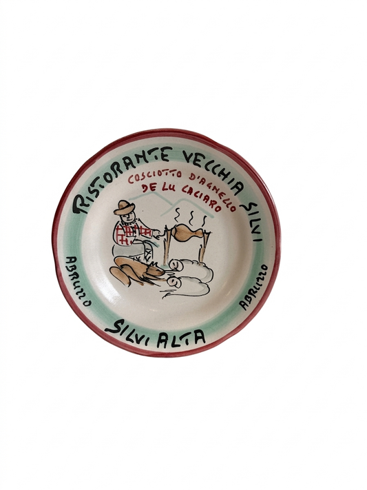 Hand-painted Buon Ricordo ceramic plate from Silvi Alta Abruzzo featuring figure roasting lamb over fire with Ristorante Vecchia Silvi text and red rim**