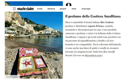 Screenshot of a Marie Claire Italia feature headlined 'Il profumo della Costiera Amalfitana', picturing the Blu Costiera Amalfi Sunset box on a rock at the Amalfi shoreline
